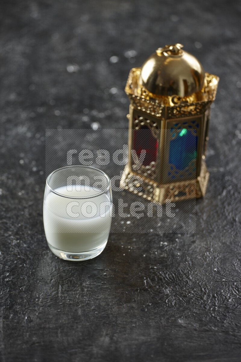 A golden lantern with different drinks, dates, nuts, prayer beads and quran on textured black background