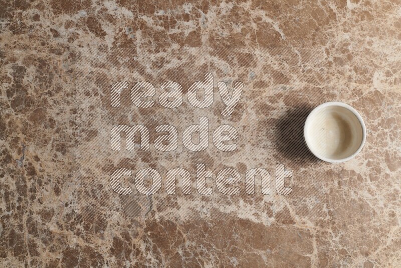 A pottery cup on beige marble background
