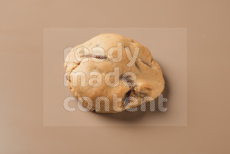 a whole chocolate chip cookie on a brown background