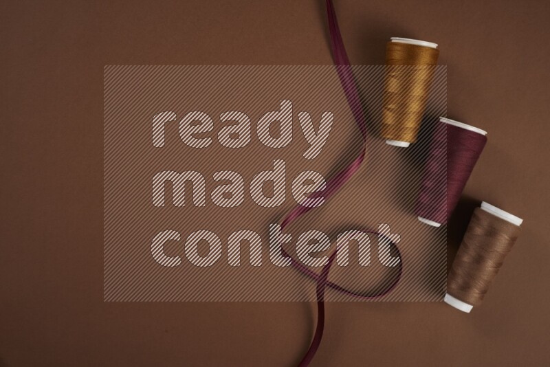 مجموعة من أدوات الخياطة والتفصيل حمراء اللون على خلفية بنية