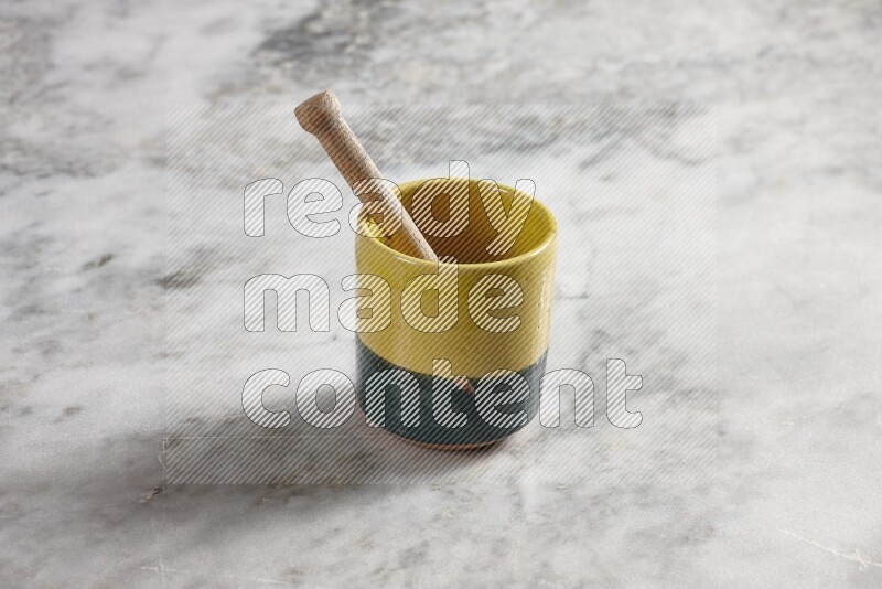 Multicolored pottery cup with wooden honey dipper in it on grey marble background