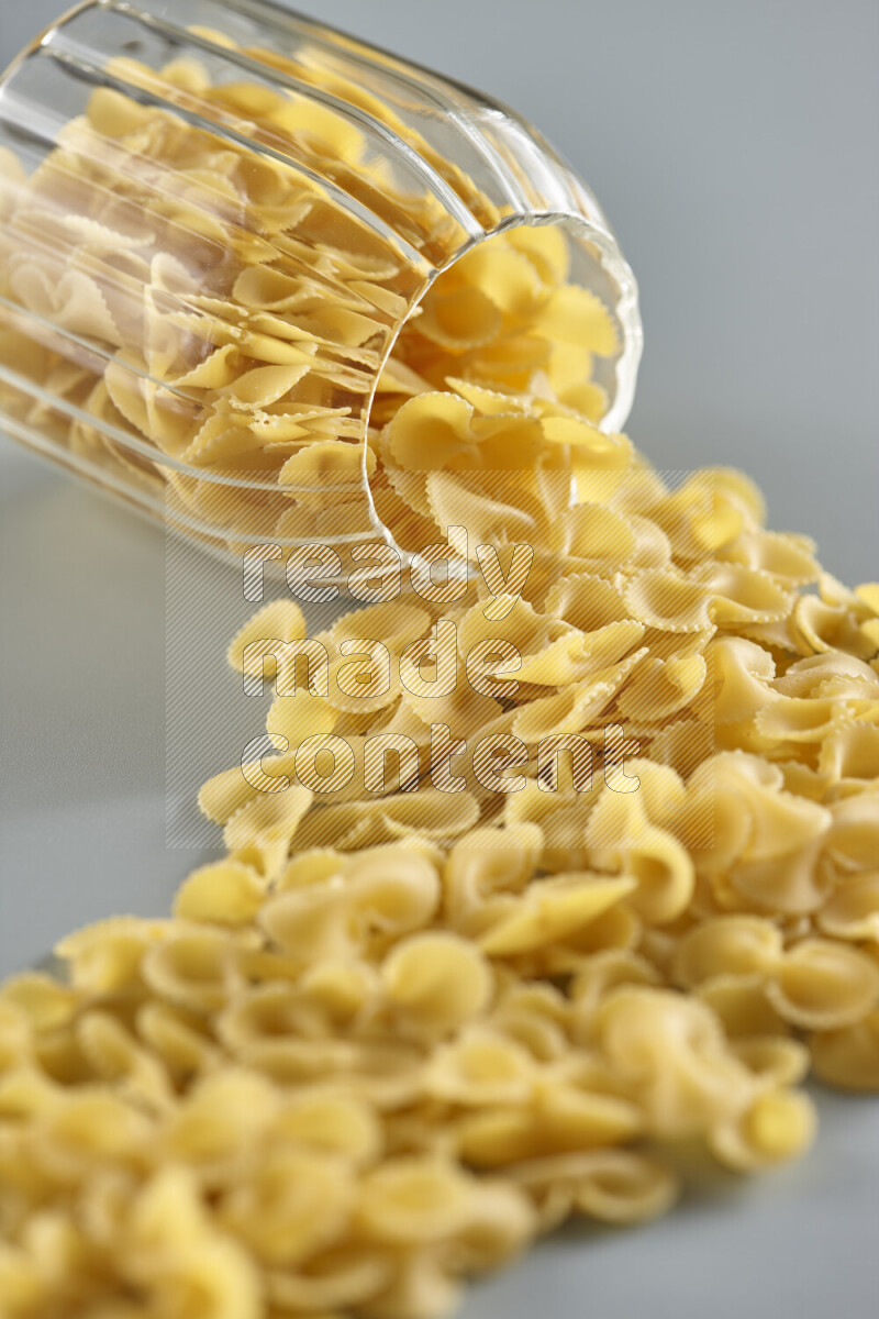 Flipped jar full of raw pasta on light blue background
