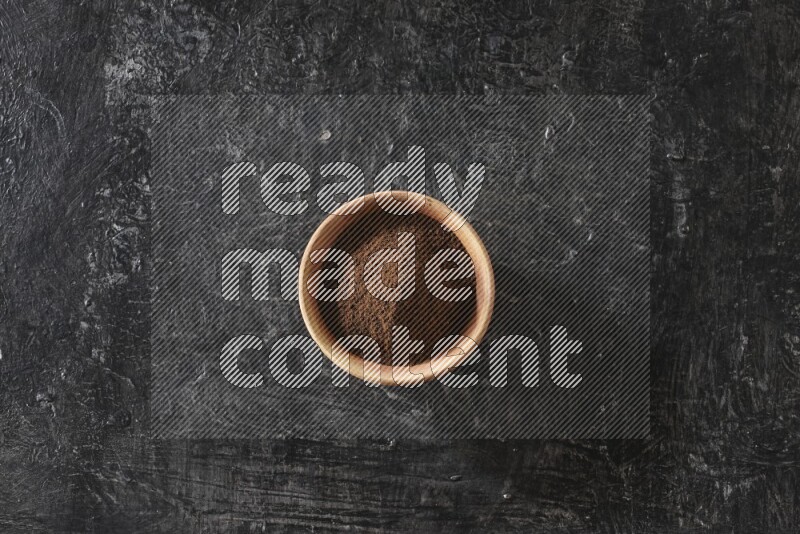 وعاء خشبي ممتلئ ببودرة القرنفل علي خلفية سوداء