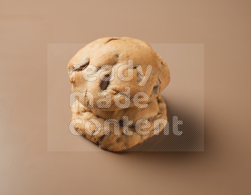 Two chocolate chip cookies on a brown background