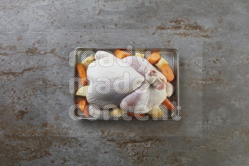 whole Raw chicken on a small oven trey direct on a rustic grey background
