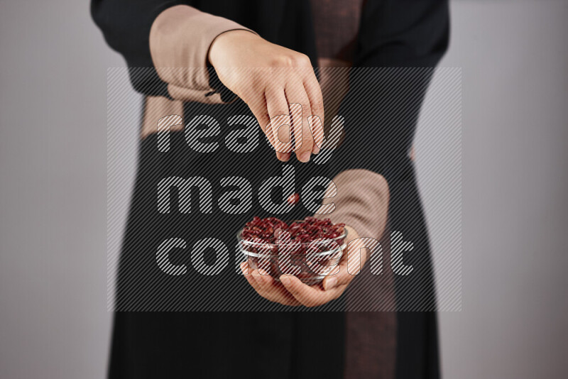 Woman in abaya holding different kinds of legumes in different positions