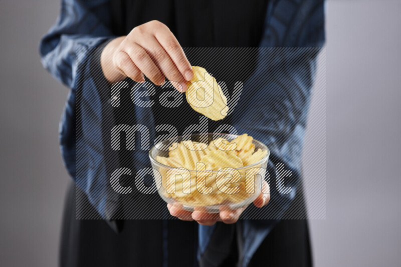 Woman in abaya holding different kinds of snacks in different positions