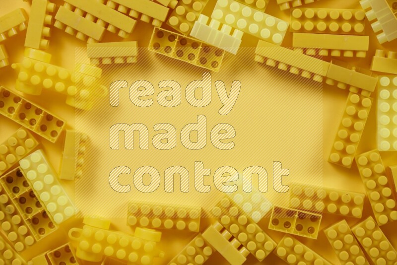 Yellow plastic building blocks on yellow background (kids toys)