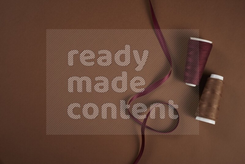 A red collection of sewing and tailoring tools arranged on a brown background