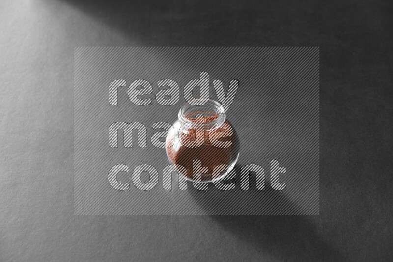 A glass spice jar full of garden cress on black flooring