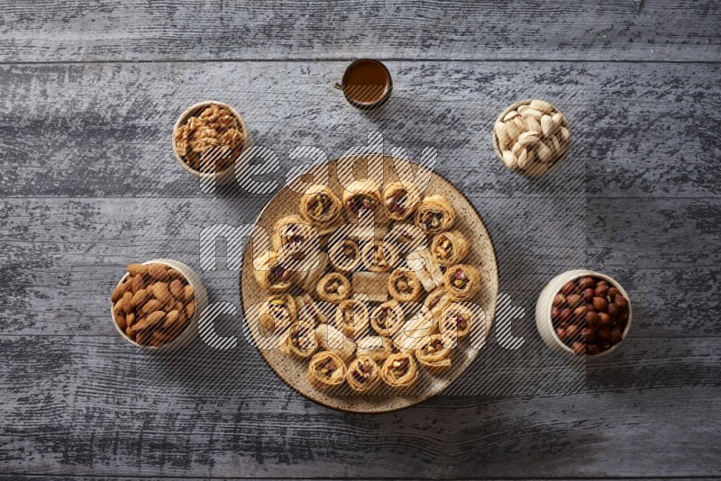Oriental sweets in a pottery plate with nuts, coffee and honey in a dark setup