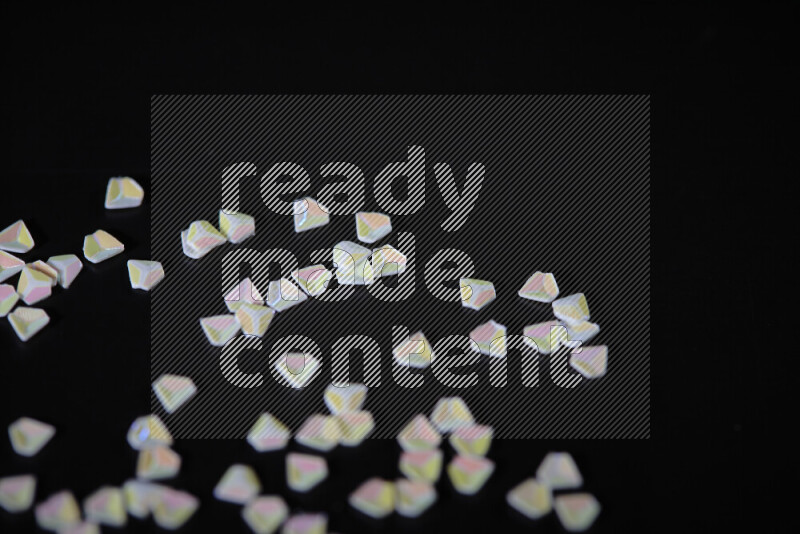 Colorful plastic shards for decoration scattered on a black background