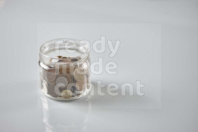 Random old coins in a glass jar on grey background
