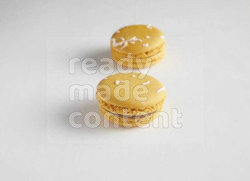 45º Shot of two Yellow Piña Colada macarons on white background