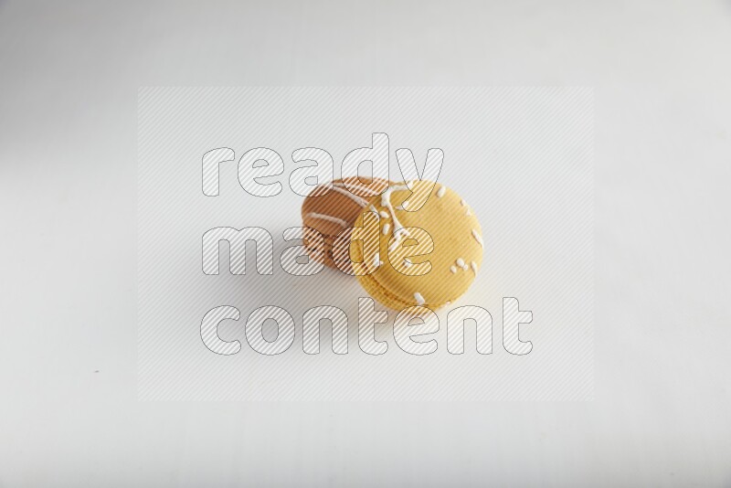 45º Shot of of two assorted Brown Irish Cream, and Yellow Piña Colada macarons on white background