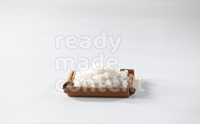 أربعة من أعواد القرفة مكونة شكل مربع بداخلها ملح أبيض علي خلفية بيضاء