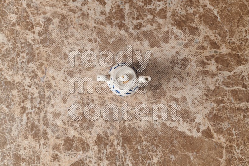 A pottery teapot on beige marble background