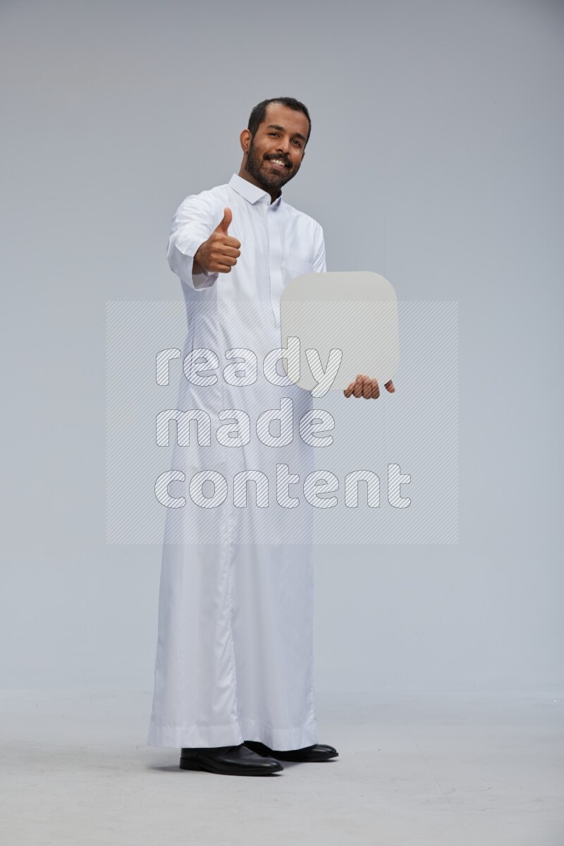 Saudi man wearing Thob standing holding social media sign on Gray background