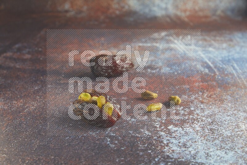 two pistachio stuffed madjoul dates on a rustic reddish background