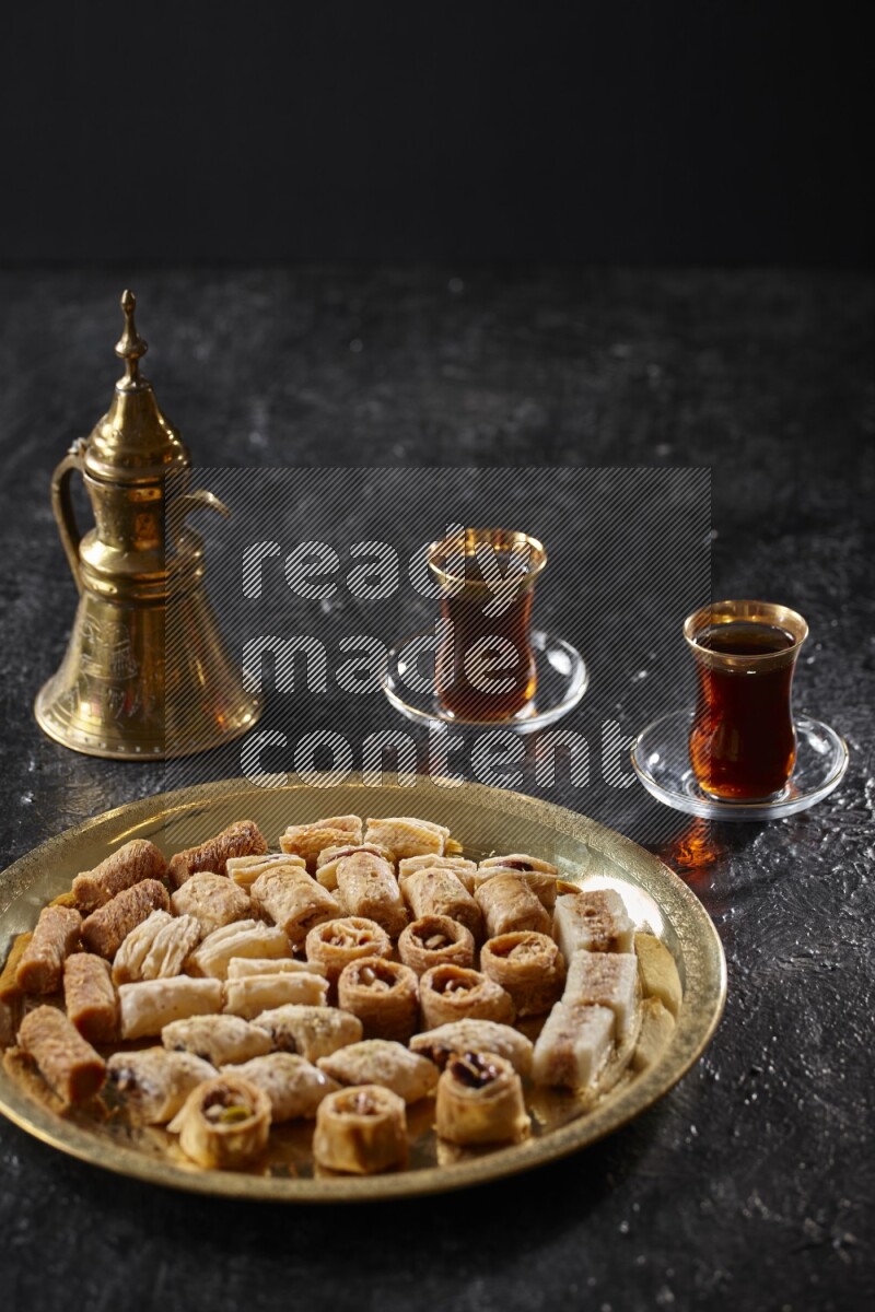 Oriental desserts with tea and a metal pot in a dark setup