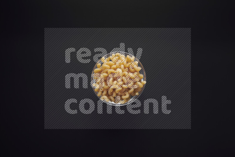 Twist pasta in a glass bowl on black background