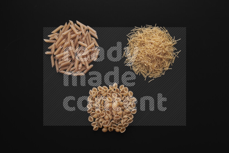 Different pasta types in bunches on black background