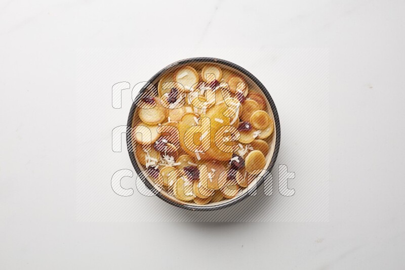 Top-view shot of orange candy cereal pancakes in a round bowl on white background