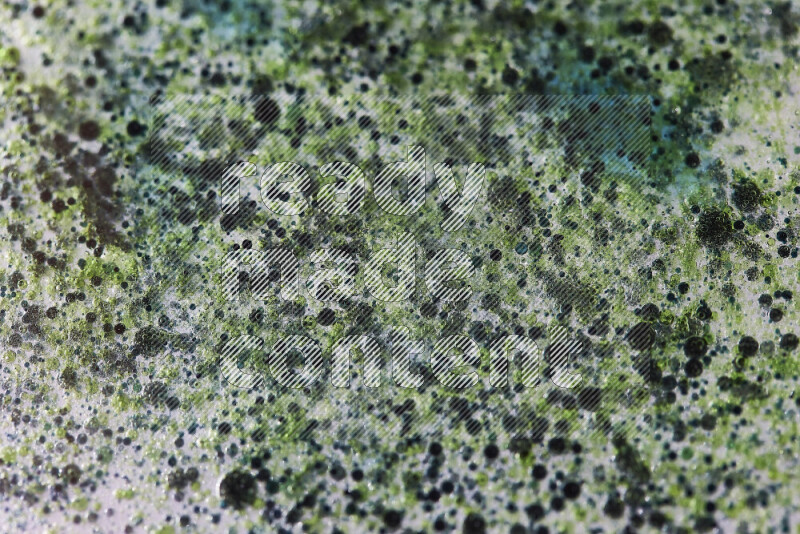 لقطات مقربة لقطرات ألوان مائية خضراء وزرقاء على سطح الزيت على خلفية بيضاء