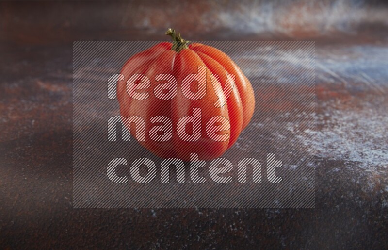 45 degree single heirloom tomato on  a textured reddish rustic metal background