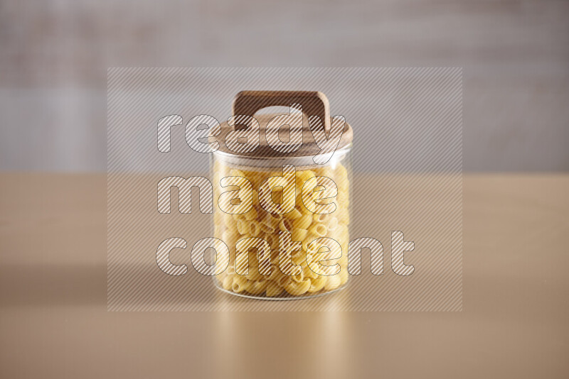 Raw pasta in glass jars on beige background