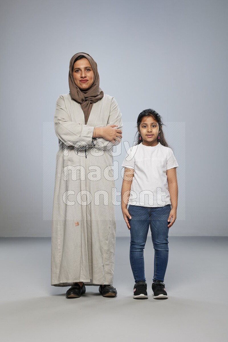 A girl and her mother interacting with the camera on gray background