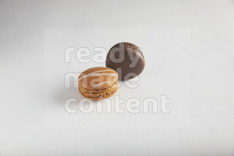 45º Shot of of two assorted Brown Irish Cream, and Brown Dark Chocolate macarons on white background