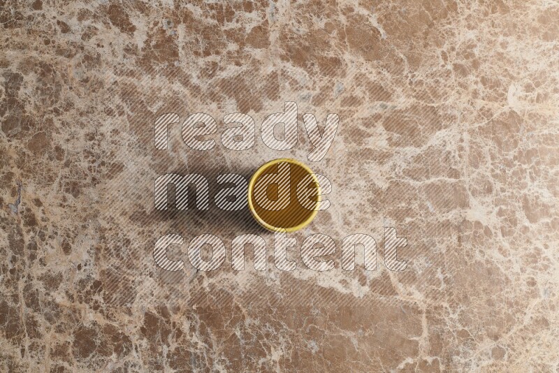 A multicolored pottery cup on beige marble background