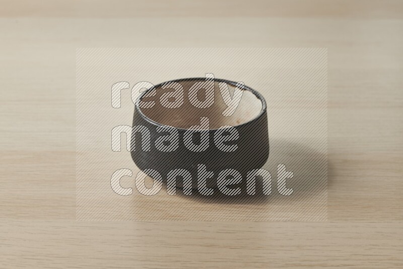 A black pottery bowl on light wooden background