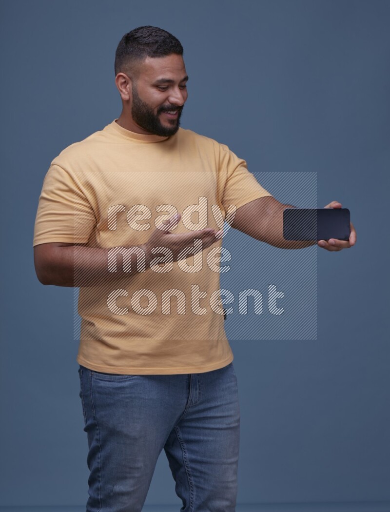 A man Showing His Smart Phone on Blue Background wearing Orange T-shirt
