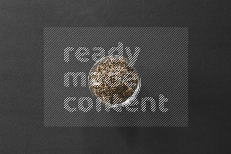 A glass bowl full of basil on black flooring