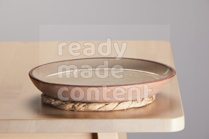 multi-colored pottery Plate placed on a small light colored straw placemat on the edge of wooden table