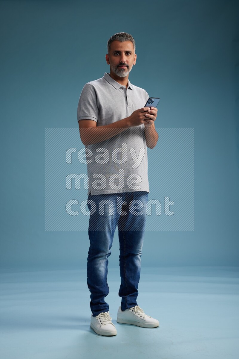 Man Standing texting on phone on blue background