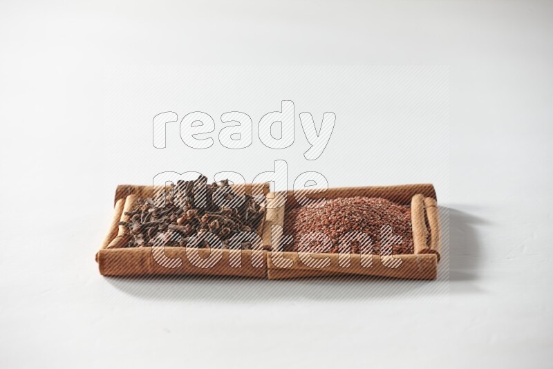 2 squares of cinnamon sticks full of garden cress and cloves on white flooring