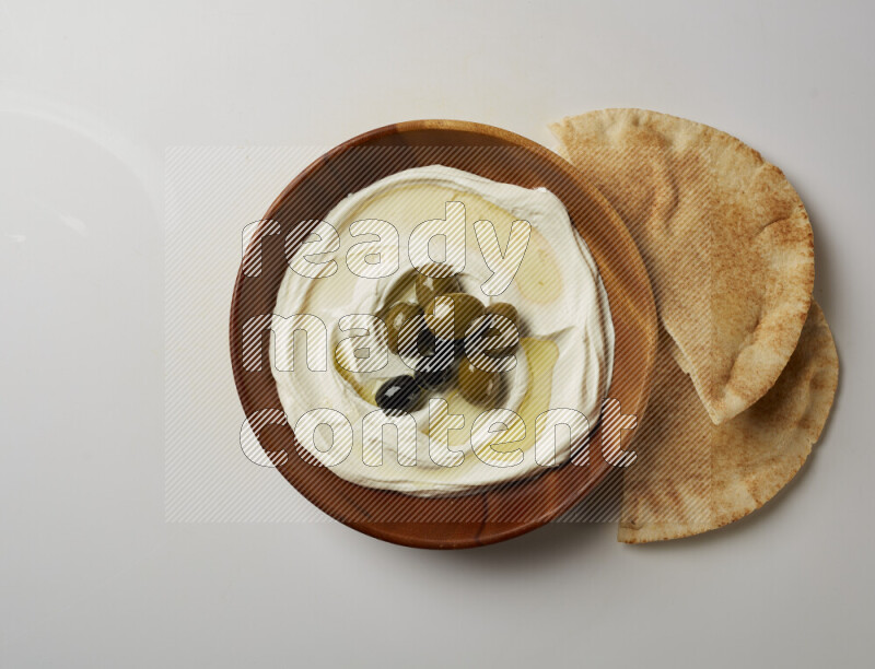 Lebnah garnished with whole olives in a wooden plate on a white background