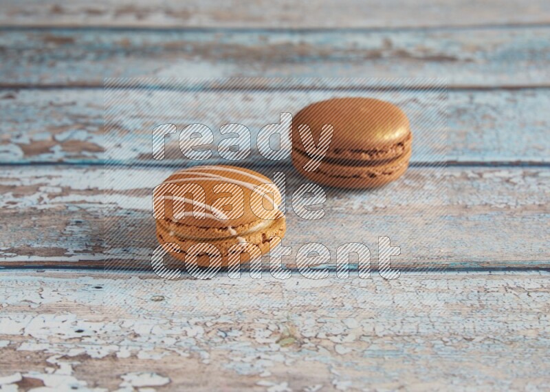 45º Shot of of two assorted Brown Irish Cream, and Brown Coffee macarons on light blue background