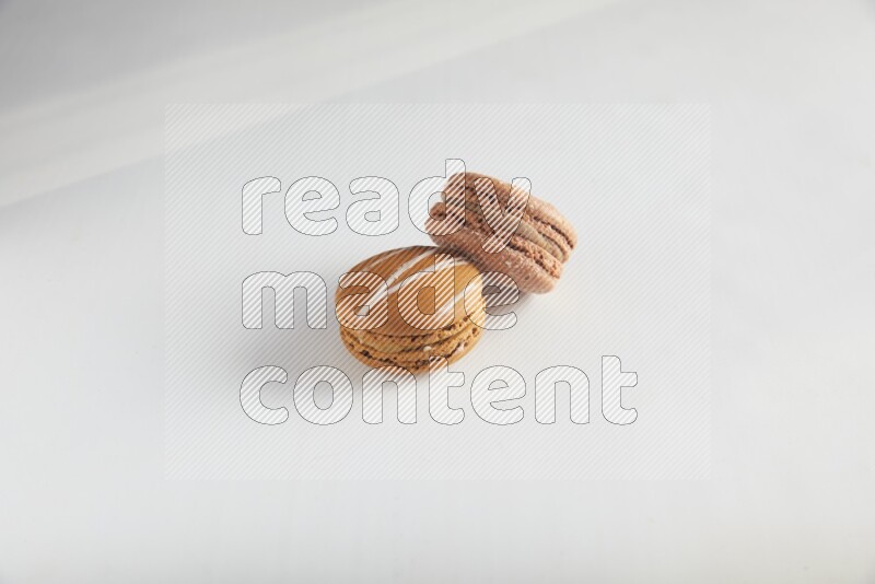 45º Shot of of two assorted Brown Irish Cream, and Brown Hazelnuts macarons on white background
