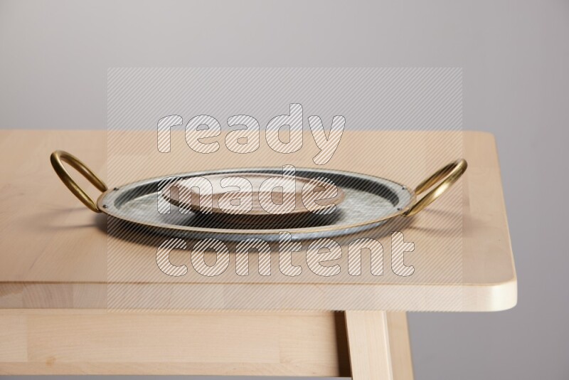 multicolored plate placed on a rounded stainless steel tray with golden handels on the edge of wooden table