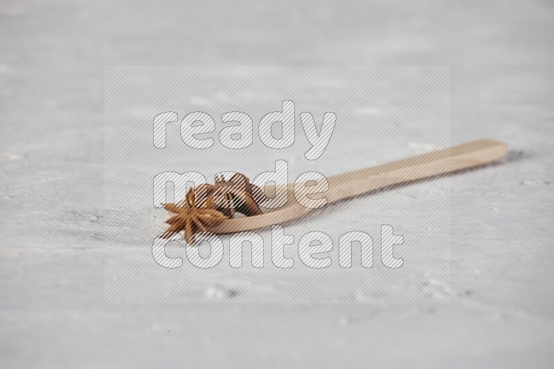 Star Anise in a wooden spoon on white flooring