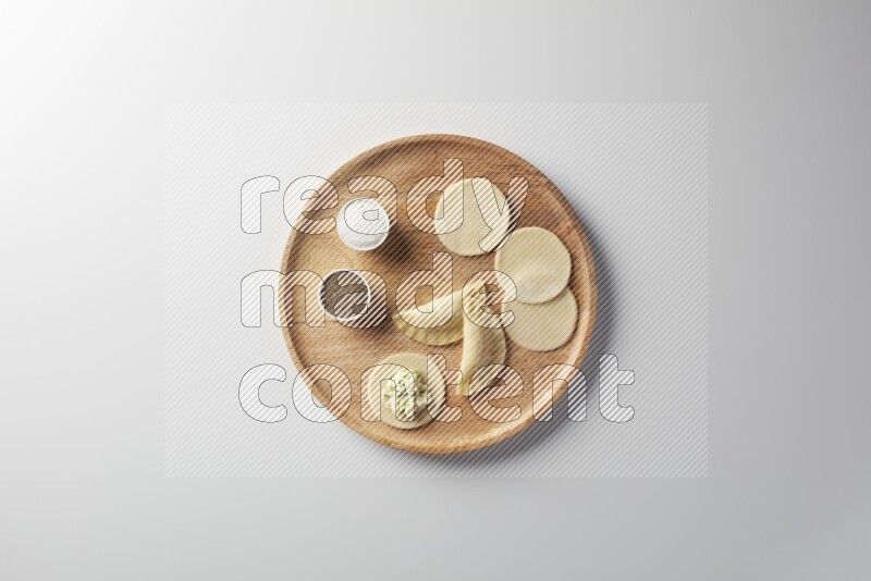 two closed sambosas and one open sambosa filled with cheese while salt, and black pepper aside in a wooden dish on a white background