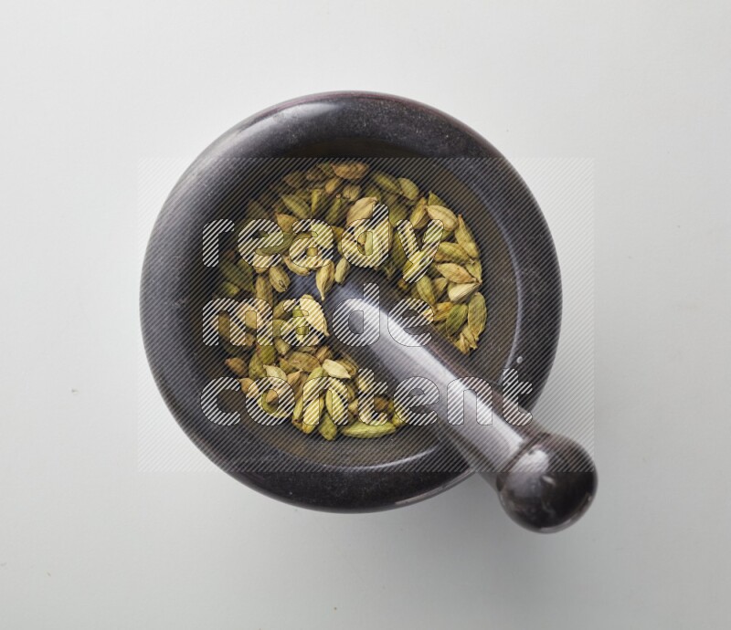 Top-view shot of Cardamon in herbs crusher on white background