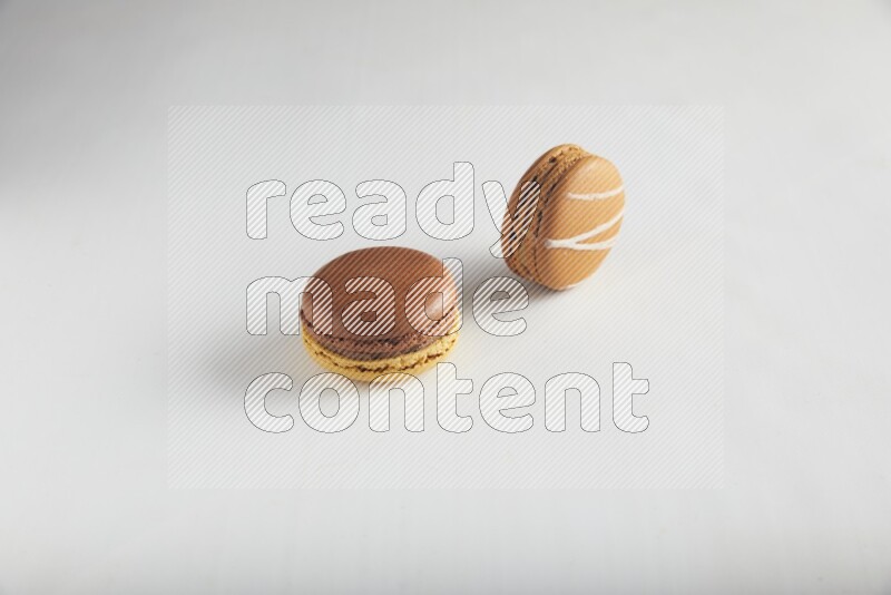 45º Shot of of two assorted Brown Irish Cream, and Yellow, and Brown Chai Latte macarons on white background