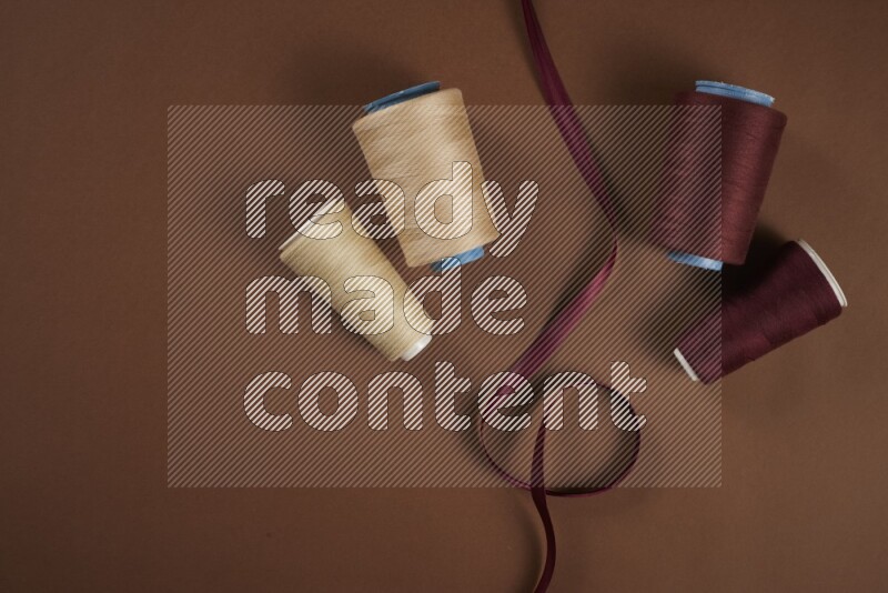 A red collection of sewing and tailoring tools arranged on a brown background