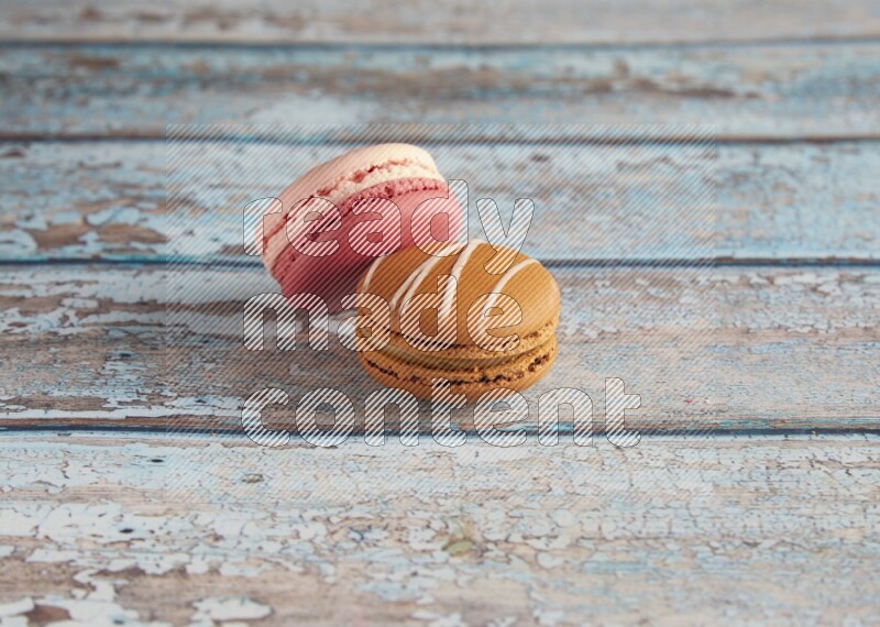 45º Shot of of two assorted Brown Irish Cream, and Pink Litchi Raspberry macarons on light blue background