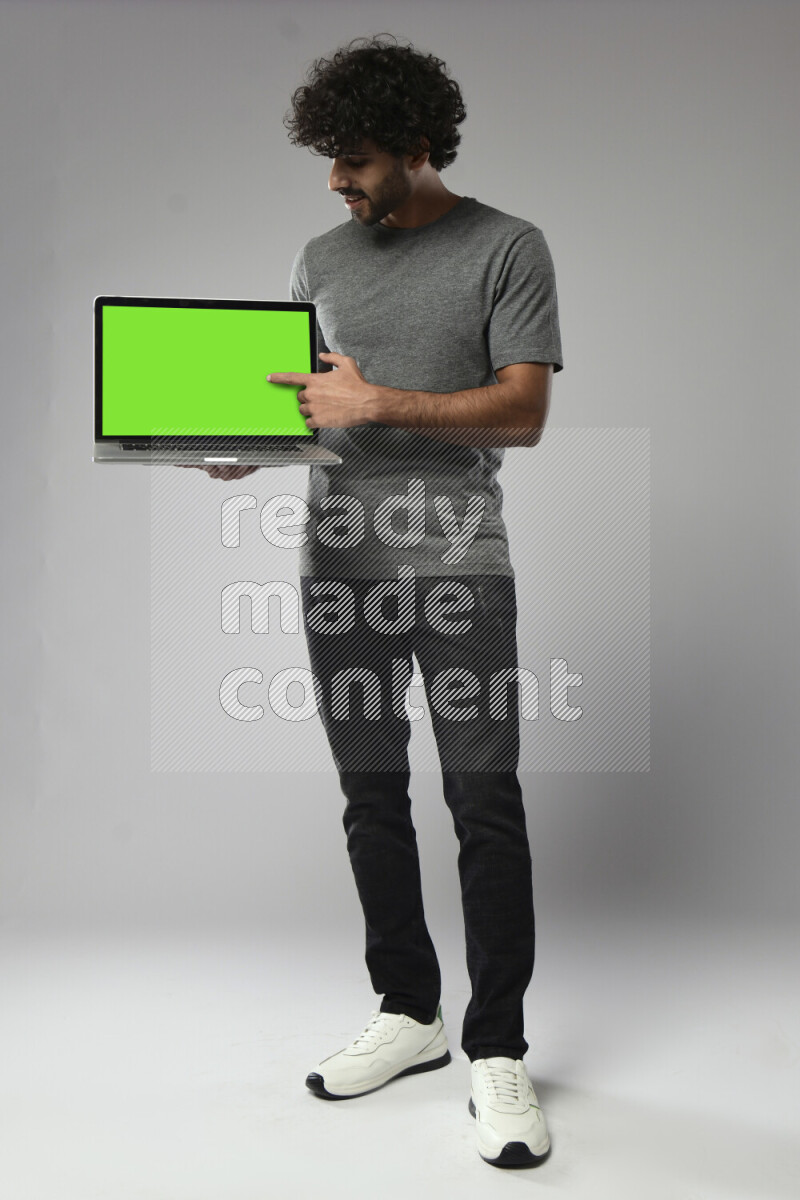 A man wearing casual standing and showing a laptop screen on white background